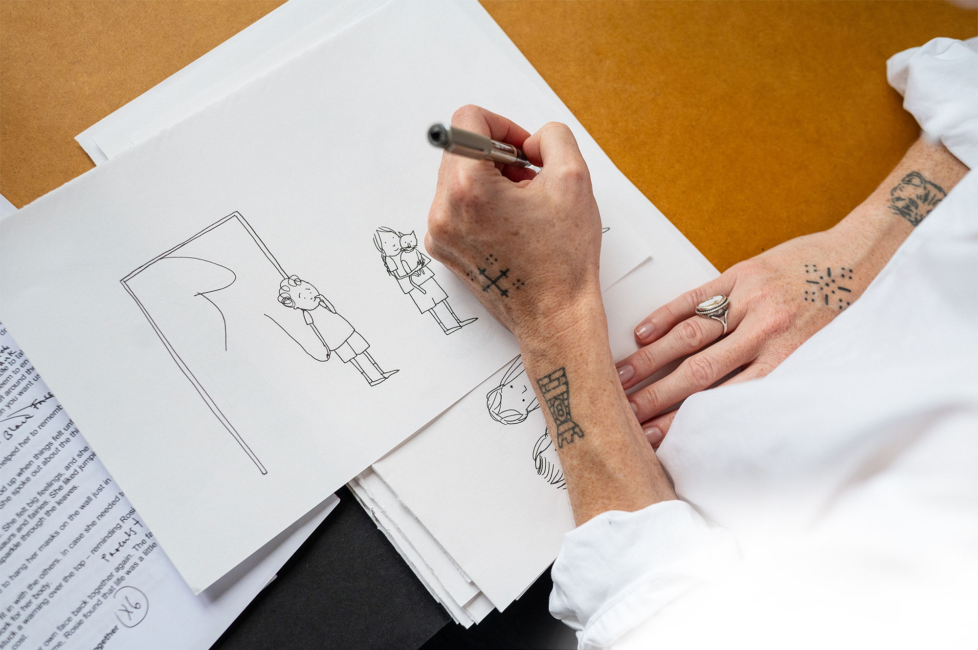 Eliza Fricker's hand pictured in in close-up as she draws illustrations for her new book